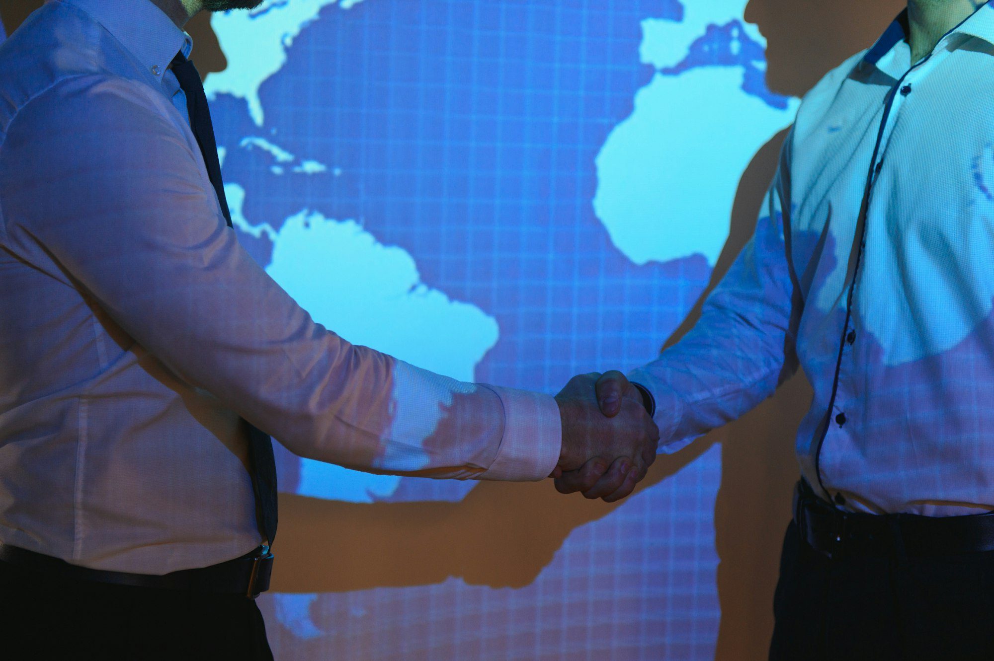 handshake with map of the world in background two businessmen on the background of the world map